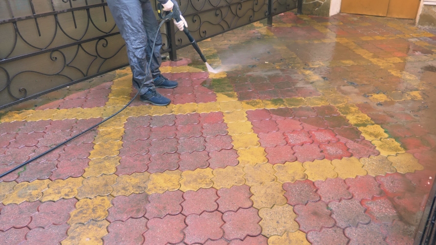 a man cleans the tile on the sidewalk from the build up of dirt