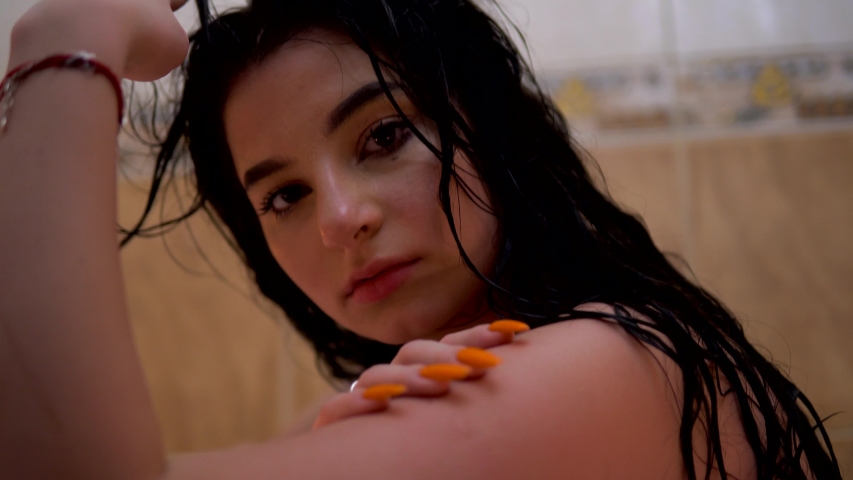 Girl sitting in bath in romantic atmosphere, looking at camera, smeared mascara