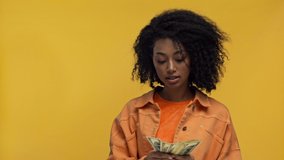 smiling african american woman counting money isolated on yellow