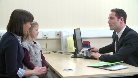 Mother and daughter in doctor's surgery discussing illness with GP sitting at desk.Shot on Sony FS700 at frame rate of 25fps