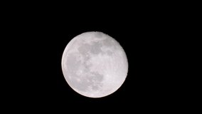 Close up of full moon with black sky background at night, clouds moving and moon light shining, telephoto lens full HD video.