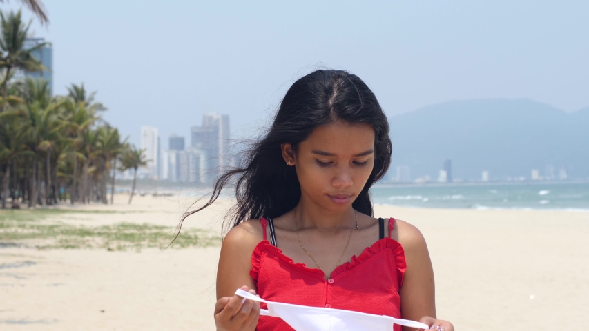 Asian woman standing in the beach wearing face mask. Health and safety concept.