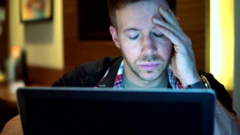 Worried Man Looking Anxiously At Laptop Screen Late At Night, 4K Stress.