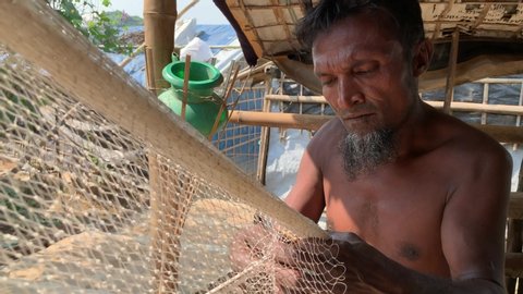 Teknaf, Bangladesh - November 2018: A Rohingya man is making a fishing net in the Teknaf refugee camp.