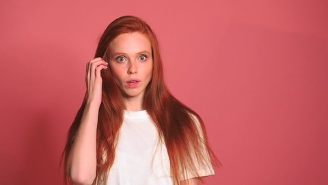 Scared shocked redhaired ginger woman in pink studio background