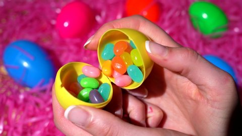 Los Angeles, CA / USA - April 4 2020: This POV video shows anonymous female hands opening a colorful easter eggs and finding jelly beans candy inside.