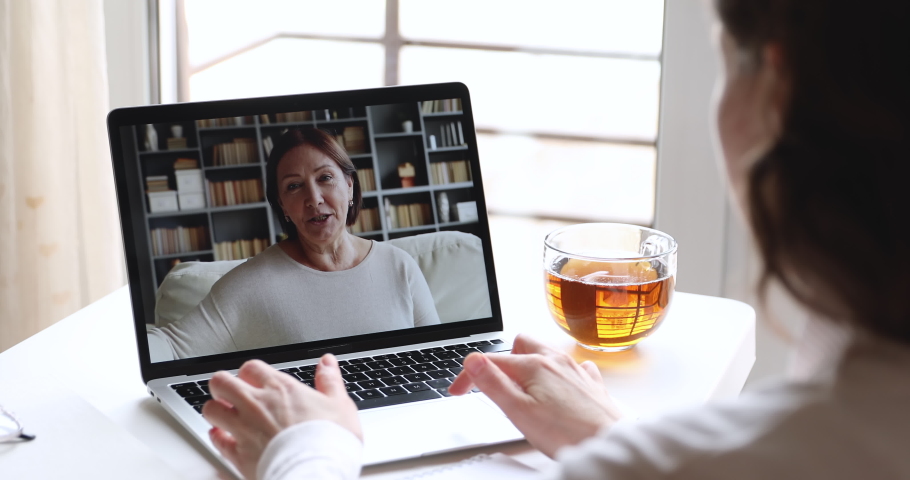 Young adult woman daughter or doctor video calling older mother patient on laptop computer screen. Two generations women talking by webcam. Videocall, family chat concept. Over shoulder close up view Royalty-Free Stock Footage #1050218941