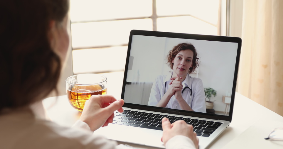 Young female patient video calling woman doctor on laptop screen. Physician consulting client in virtual chat computer app. Remote telemedicine medical services concept. Over shoulder closeup view Royalty-Free Stock Footage #1050218944