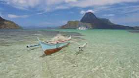 Traditional fishing banca boat floating in blue lagoon of El Nido bay, Palawan, Philippines. Cadlao island in background