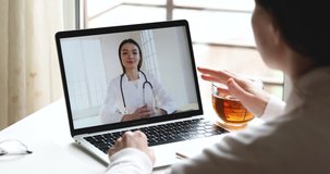 Over shoulder closeup view of young woman talking with female doctor in online conference webcam video chat on laptop screen discuss healthcare problem. Remote call telemedicine consultation concept.
