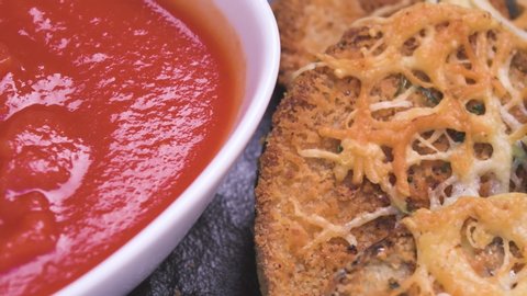 Eggplant Slices Breaded with Tomato Sauce on Black Plate Over Wood