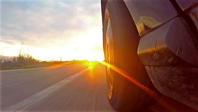 UHD Timelapse of sport car driving down narrow road toward sun rays at sunset, sunrise.4K shot