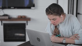 Girl sitting at home at the table in front of a laptop. Work from home. Young beautiful woman businessman working at a distance. Distance learning during quarantine.