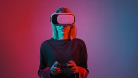 Young woman in VR glasses. A woman immersed in virtual reality play video game. Blue and red light falls on a woman on a black background.
