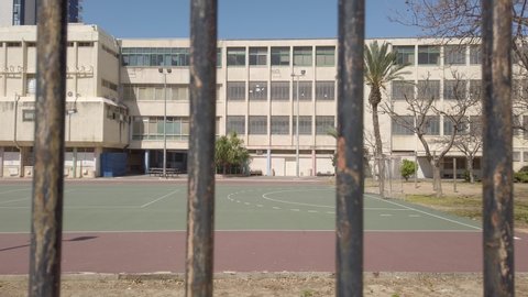 Camera pull out from school to a gate or metal fence - empty school during break