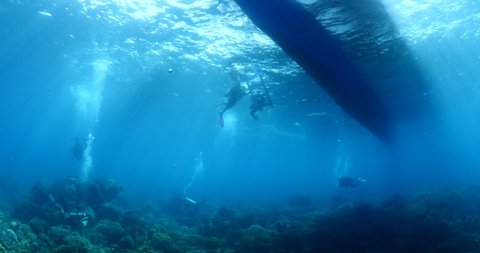 scuba diver scenery under the boat in tropical waters with fish and corals