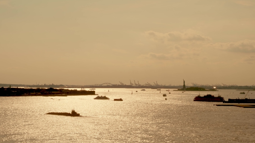Water traffic on the Hudson River around Statue of Liberty at sunset while The Staten Island Ferry departing, New York