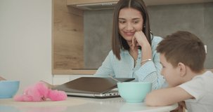 Brother and sister have dinner. Mother feeds children. Family having lunch in kitchen. Young woman working from home. Self-isolation. 4k video footage slow motion