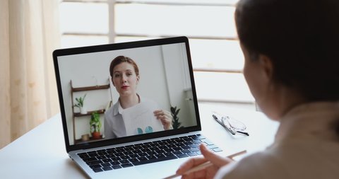 Videoconference meeting concept. Female manager discussing financial report with distance partner making webcam presentation elearning training conference video call. Over shoulder laptop screen view