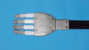 A mechanical hand flexes its fingers and shows a rock sign. Gray cyborg arm came to life and began to move on a blue background. Vertical video.