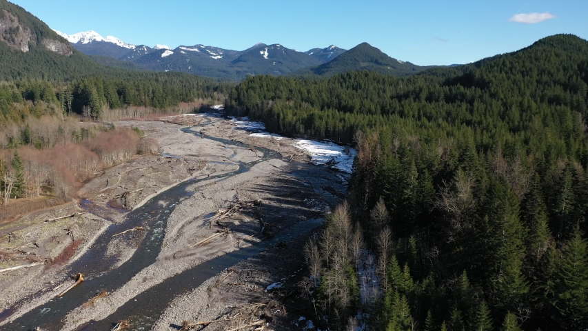 Aerial / drone footage of the Nisqually River with Cascade range in the background by Mt. Rainier National Park in Washington