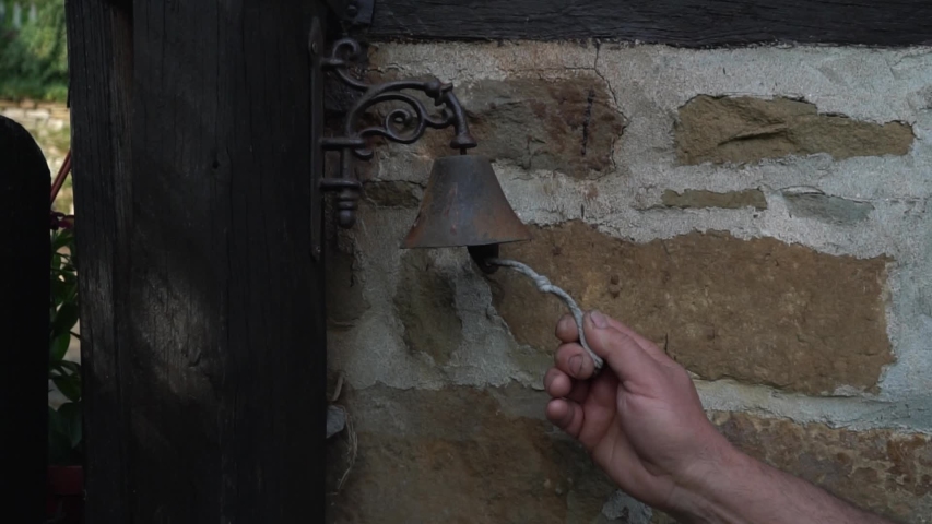 Close up man hands beats vintage old bell at the front door of an old house slow motion