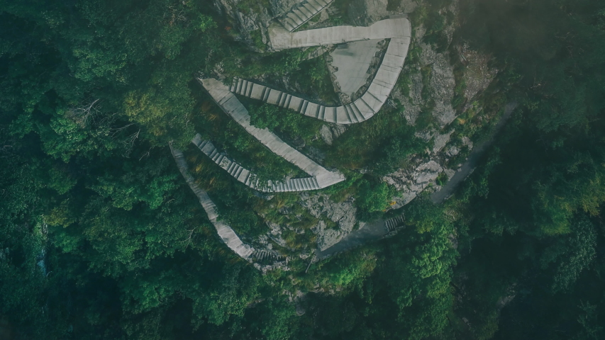 Twisting mountain stairs surrounded by trees with mist and fog aerial