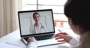 Telemedicine videoconference concept. Friendly female doctor consulting woman client patient by video call remote healthcare web cam app chat on laptop. Over shoulder closeup computer screen view