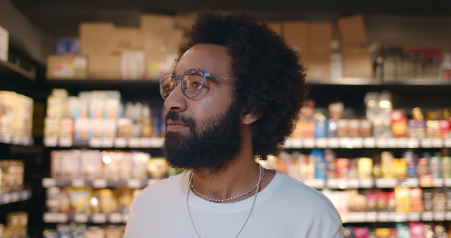 Close up of handsome man in glasses walking and looking around in supermarket. Mature guy in 30s searching for products while doing shopping in grocery store.Blurred background. Royalty-Free Stock Footage #1050317029