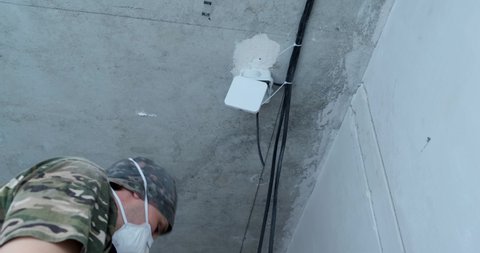 Electrician at work, construction site, handyman in respiratory, breathing protection, pandemic work, dust and virus protection, cable on ceiling, wire trimming, electrical wiring, de-energized room
