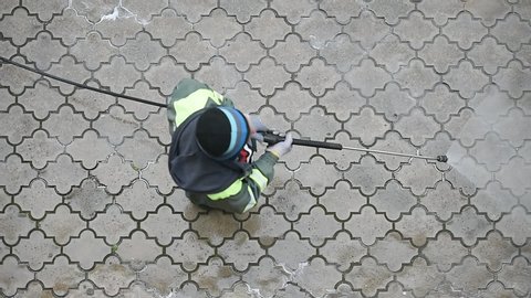 Public janitor deep cleaning the sidewalk with high pressure disinfectant solution in times of corona virus pandemic in a lockdown Bucharest, Romania.
