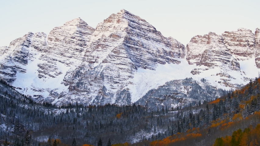 Maroon Bells morning sunrise timelapse with yellow sunlight on peak in Aspen, Colorado rocky mountain and autumn foliage view closeup and winter snow