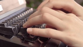 female hands with manicure typing on an old typewriter.
