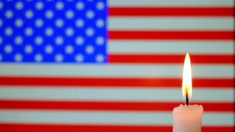 Mourning in USA . Burning candle on the background of the flag of USA . 