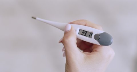 Coronavirus symptom. Electronic thermometer showing fever of 39.1 degrees Celsius in female hand