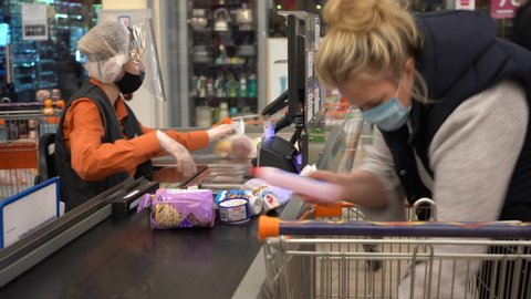 Europe, Kiev, Ukraine - April 2020: a buyer in a medical mask pays for products at the checkout in a supermarket during the Covid-19 coronavirus pandemic. Cash desk at the supermarket.