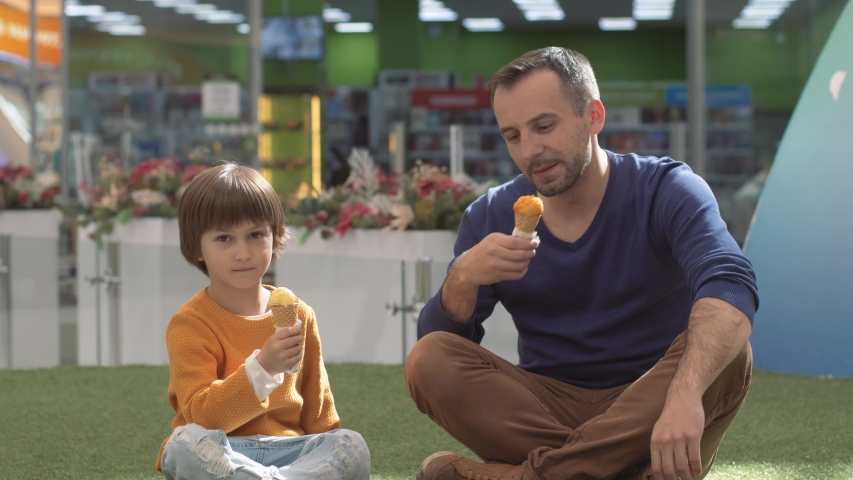 Father and son enjoying icecream outside in a park