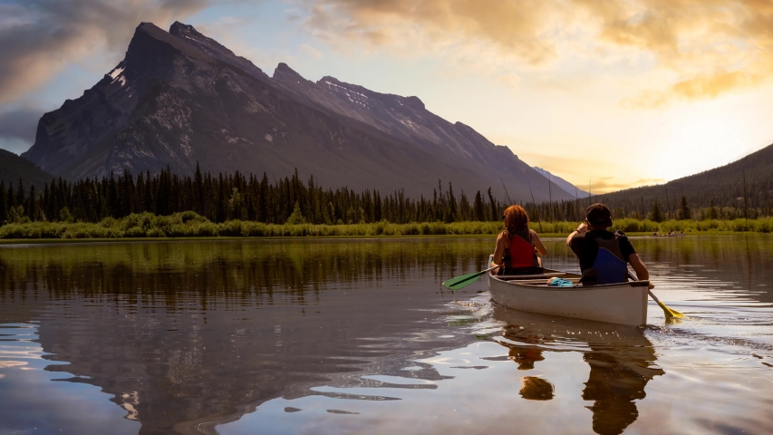 Cinemagraph Continuous Loop Animation. Couple adventurous friends are canoeing in a lake surrounded by the Canadian Mountains. Taken in Vermilion Lakes, Banff, Alberta, Canada.