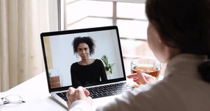 Online job interview concept. African business woman manager conferencing in app talking with female applicant, remote employee working from home office by webcam video call. Over shoulder screen view
