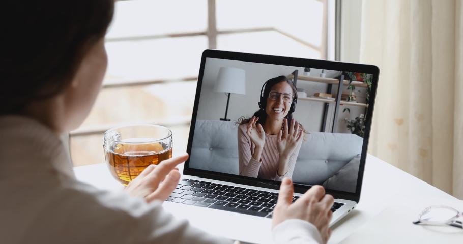 Happy young online teacher wears headset communicates with distant student gives web education class talks in webcam chat video conference call on laptop screen. Elearning concept. Over shoulder view Royalty-Free Stock Footage #1050346030