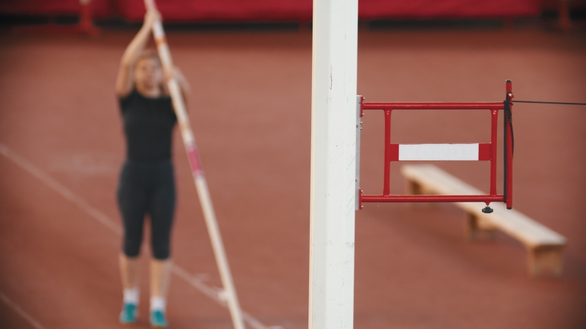 Pole vault training on the stadium - woman running up and jumping over the bar touching it