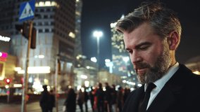 Bearded mature entrepreneur or office worker using transparent holographic smartphone interface internet app in futuristic city center outdoors. Close-up, portrait. - Powered by Shutterstock - Get 15% off with code: PIKWIZARD15