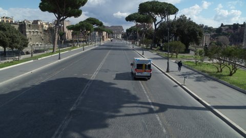 ROME, Italy – March 28, 2020: Aerial drone flight on the Via dei Fori Imperiali showing an ambulance heading toward the Colosseum in Rome during the Covid-19 epidemic shutdown.