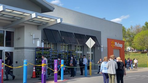 Ellicott City, Maryland / USA - April 11, 2020: Shoppers line up outside of Walmart amid the COVID-19 pandemic. Many choose to wear masks to protect themselves and others against the virus.