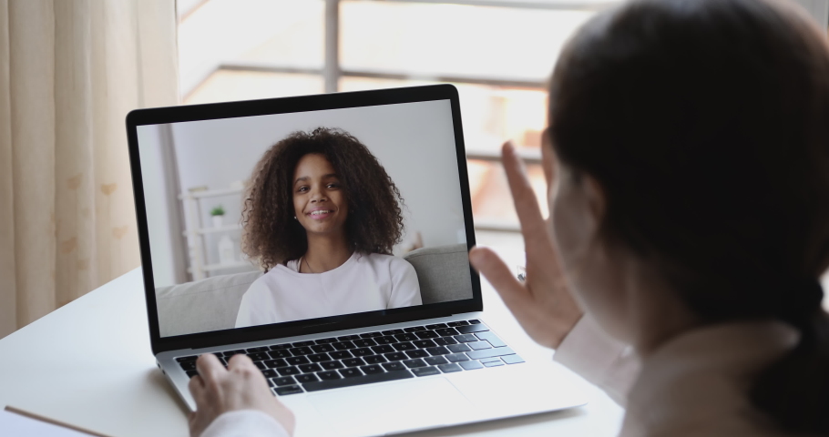 Over shoulder view of caucasian online teacher, remote tutor or psychologist conferencing with african school girl student on distance learning video call at home. Online study by webcam chat concept Royalty-Free Stock Footage #1050359014