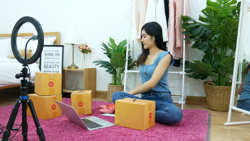 4K. Asian woman live streaming for selling shoe, fashion accessories online on social media via mobile phone from bedroom at home. owner of small business working from home during self isolation Royalty-Free Stock Footage #1050362614