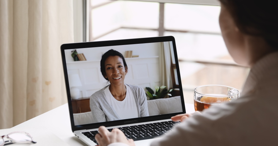 Over shoulder view of female psychologist consulting african woman client during online counseling therapy session using computer video call distance web cam chat app concept. Laptop screen closeup. Royalty-Free Stock Footage #1050364021