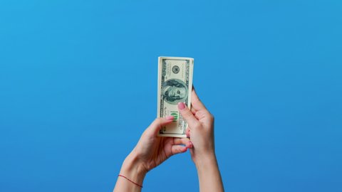 Hands counting dollar bills and throwing money cash on blue background