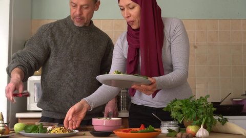 Ramadan, Eid al-Fitr, Festival of Breaking the Fast. Authentic muslim husband and wife cooking together at home. Middle-aged happy modern arabic family couple preparing food in a kitchen. Slow Motion