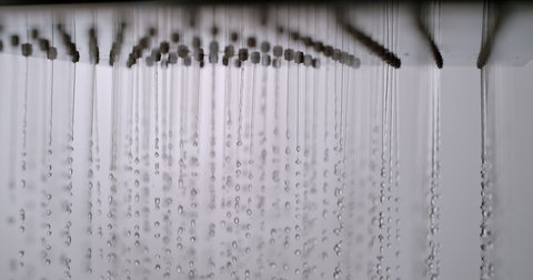 close up water drop falling from a shower in slow motion. water flow from a shower on a white background